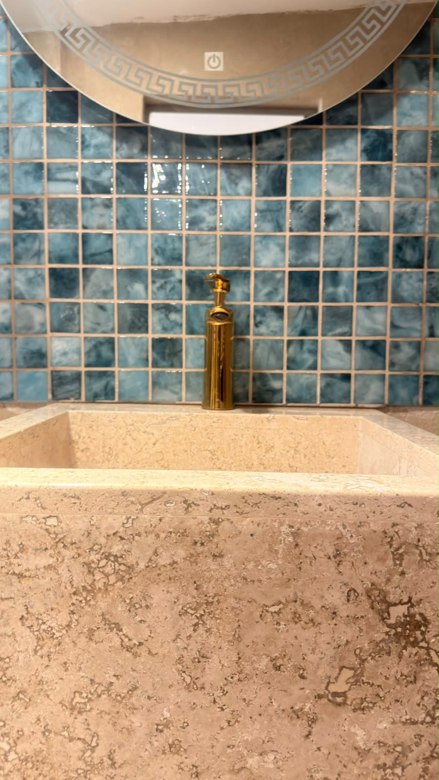 Lavabo de mármol con azulejo azul y grifería dorada