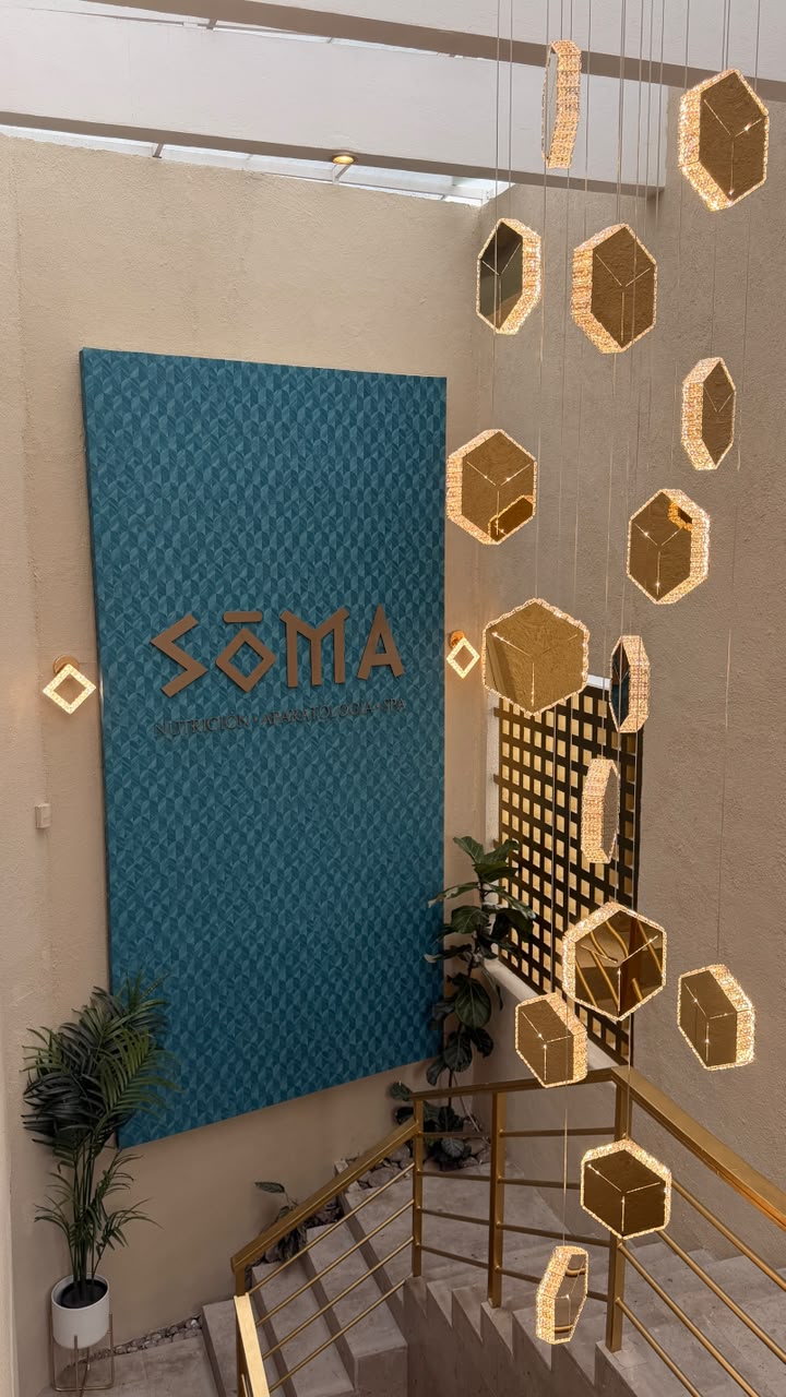 Escalera de acceso con lámparas doradas y mural SOMA