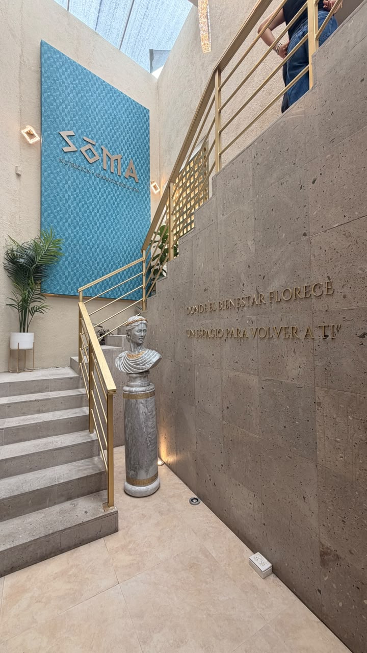 Busto griego junto a la escalera y el mural SOMA
